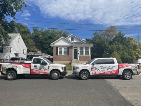 Two American Construction trucks in front of a house